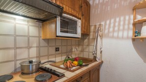 A kitchen with wooden cabinets, a microwave, a stove, and a sink.