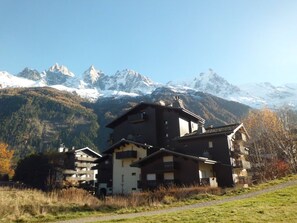 A multi-story building with a traditional architectural style, situated in a mountainous area with snow-capped peaks in the background.