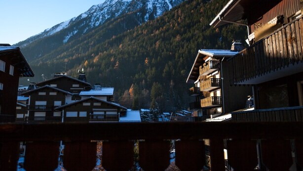 A mountain village with wooden buildings and a snow-covered peak in the background.