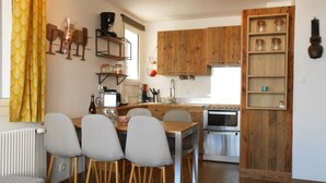 Eine kleine Küche mit Holzausstattung, einem eingebauten Backofen und einem Essbereich mit vier Stühlen.