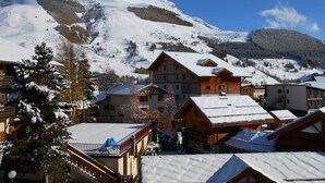 Ein verschneites Bergdorf mit Holzhäusern und einer Skipiste.