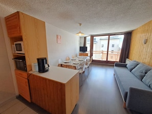 A compact living space with a kitchenette, dining area, and a sofa.