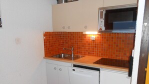 A compact kitchen with a microwave, sink, and dishwasher.