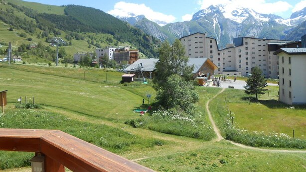 A hotel with multiple buildings, a grassy field, and mountains in the background.