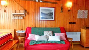 Una habitación acogedora de madera con una cama, una mesita, una silla y un radiador.