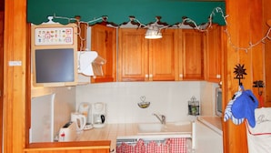 Una cocina con armarios de madera, una cafetera, un hervidor y un lavamanos.
