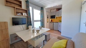 A compact living space with a kitchenette, a dining area, and a sofa with a yellow pillow. - Studio at the slopes of Les Deux Alpes (Les Deux Alpes)