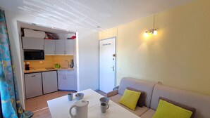 A compact living space with a kitchenette, a dining area, and a sofa with cushions. - Studio at the slopes of Les Deux Alpes (Les Deux Alpes)