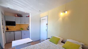 A compact room with a bed, a kitchenette, and a door leading to another room. - Studio at the slopes of Les Deux Alpes (Les Deux Alpes)
