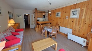 A cozy living room with a wooden sofa, a dining table, and a kitchen area. - Studio for 4, center of Les Deux Alpes, pets allowed (Les Deux Alpes)