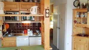Une cuisine compacte dotée d’armoires en bois, d’un four à micro-ondes, d’une machine à café et d’un évier.