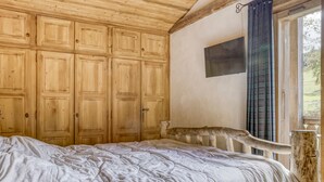 Un dormitorio con una cama grande, un armario de madera y una ventana con cortinas.