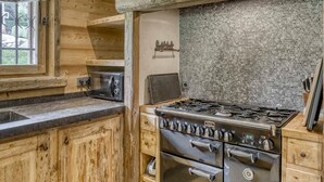 Una cocina rústica con armarios de madera, estufa a gas y protector contra salpicaduras de ladrillo.