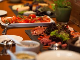 Uma mesa com diversos alimentos, incluindo tomates fatiados, carnes e folhas.