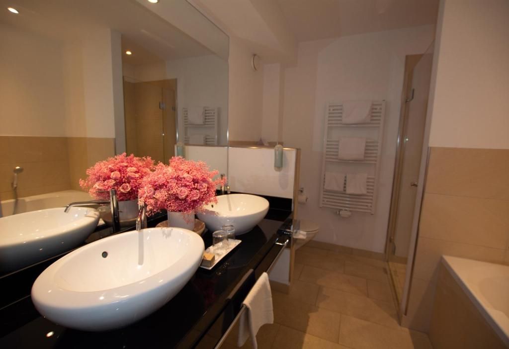 A bathroom with two sinks, a mirror, and a shower area.
