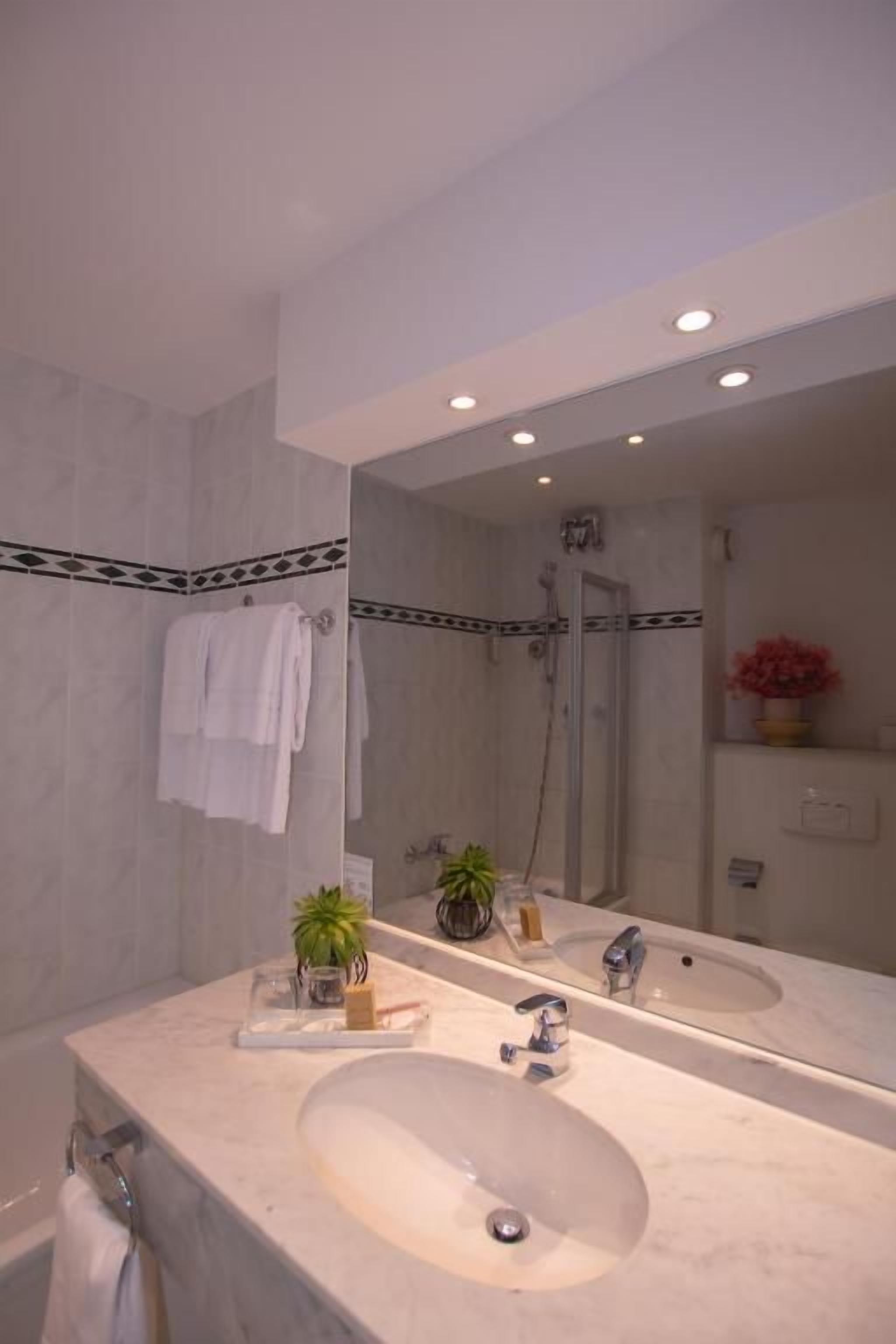 Ein Badezimmer mit einem großen Spiegel, zwei Waschbecken, einer Dusche und einem Handtuchhalter.