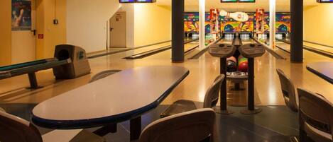 A bowling alley with multiple lanes, bowling pins, and a scoreboard.
