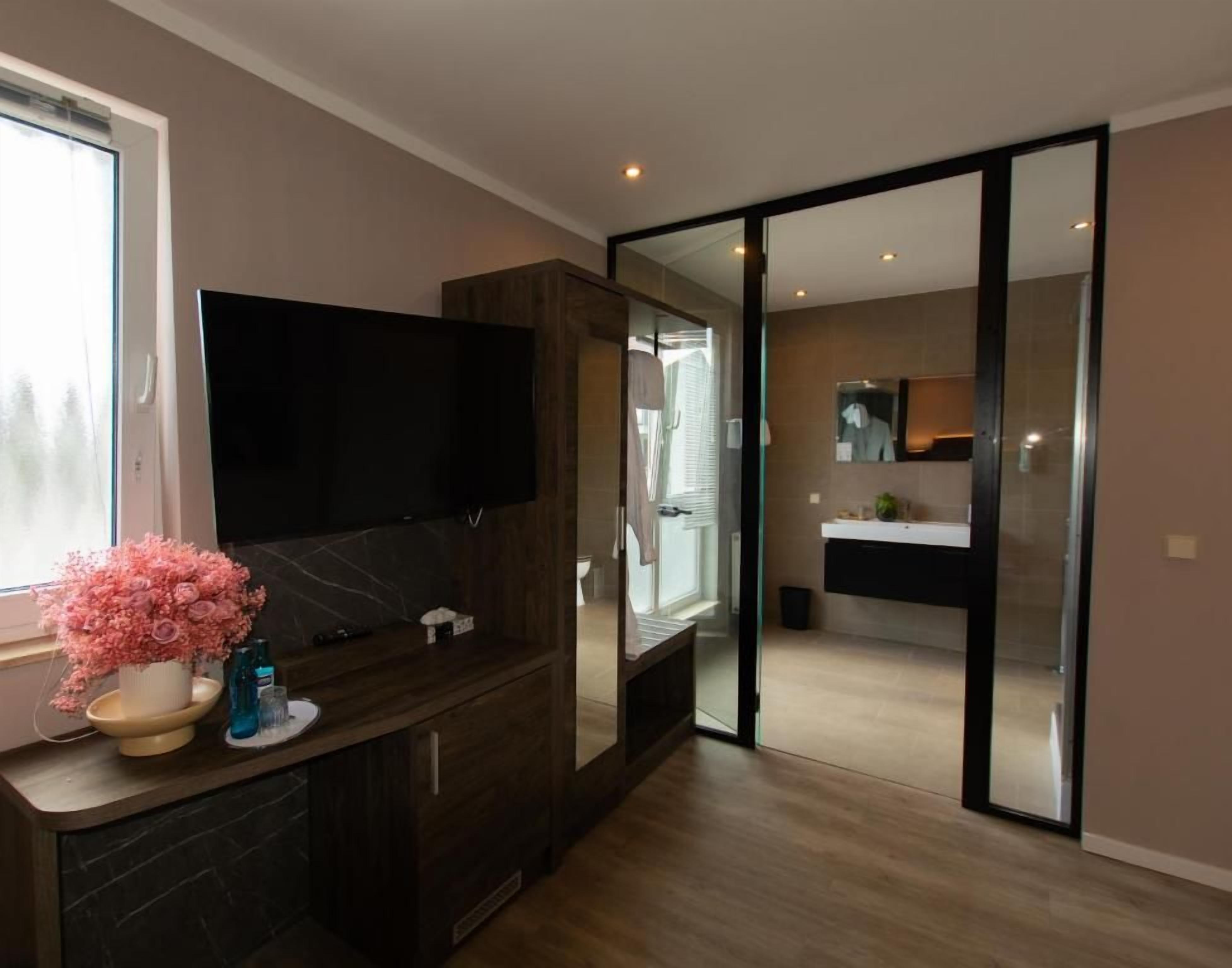 A modern bathroom with a large mirror, a sink, and a toilet.