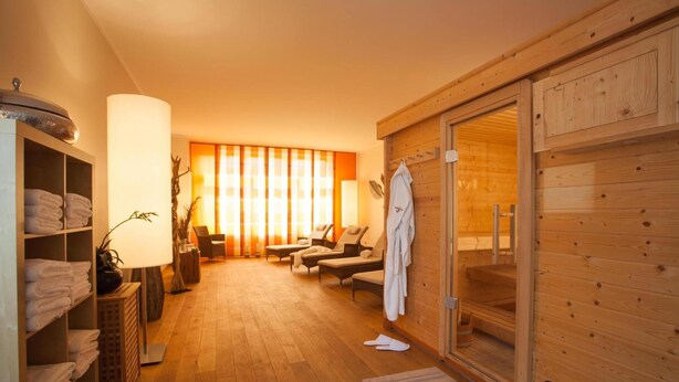 Una sala de sauna con paredes de madera, un banco y un perchero para toallas.