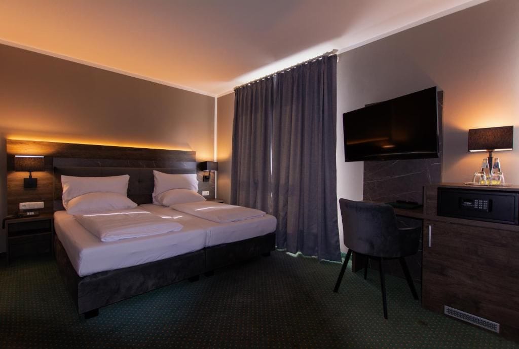 A hotel room with a bed, a desk, a television, and a chair.