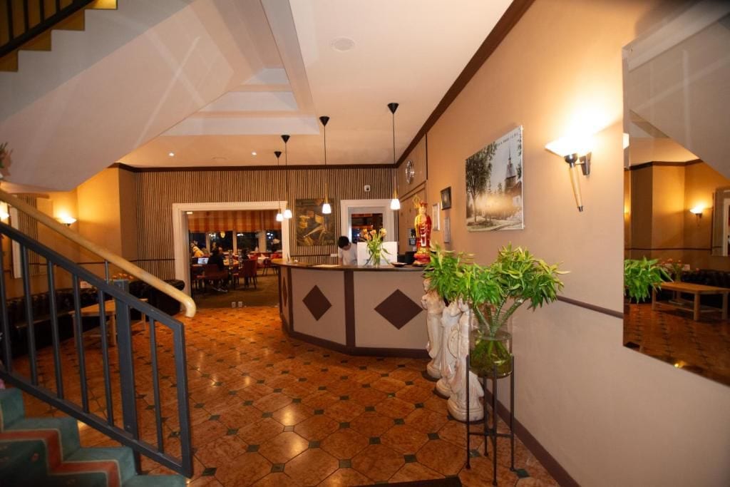 Eine Hotelhalle mit Empfangsbereich, Treppe und Essbereich.