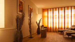 Una sala de estar moderna con piso de madera, un sofá, un sillón y dos grandes cuadros abstractos en la pared.