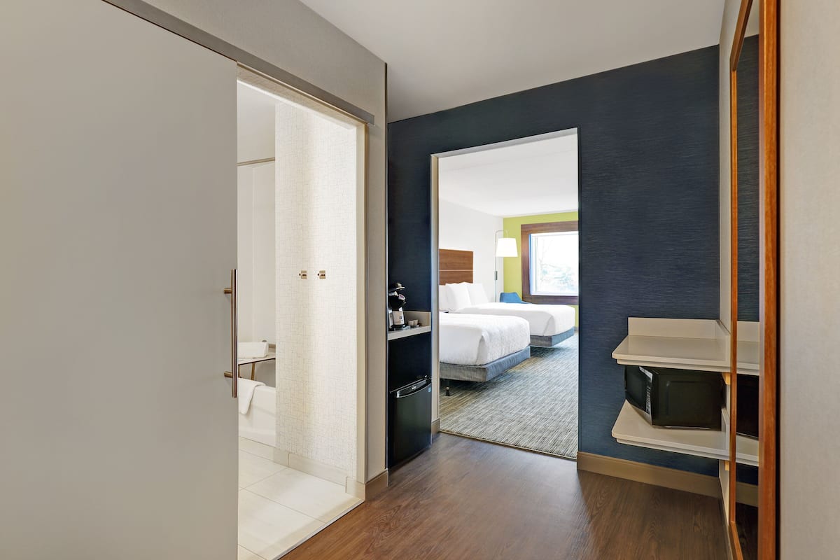 Una habitación de hotel con una cama, un escritorio y un microondas.