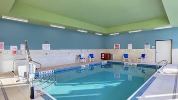 A swimming pool with lane markers, safety signs, and lounge chairs.