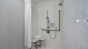 Eine Dusche mit Duschbrause, einer Handbrause und einem Handtuch auf einem kleinen Tisch.