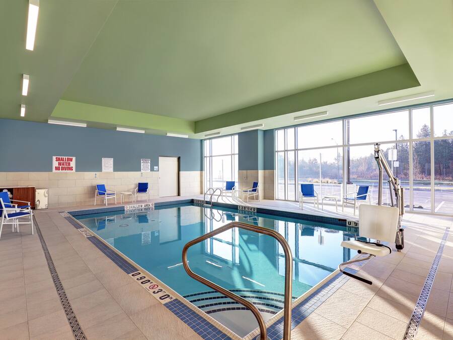 An indoor swimming pool with clear lane markings, blue chairs, and safety signs.