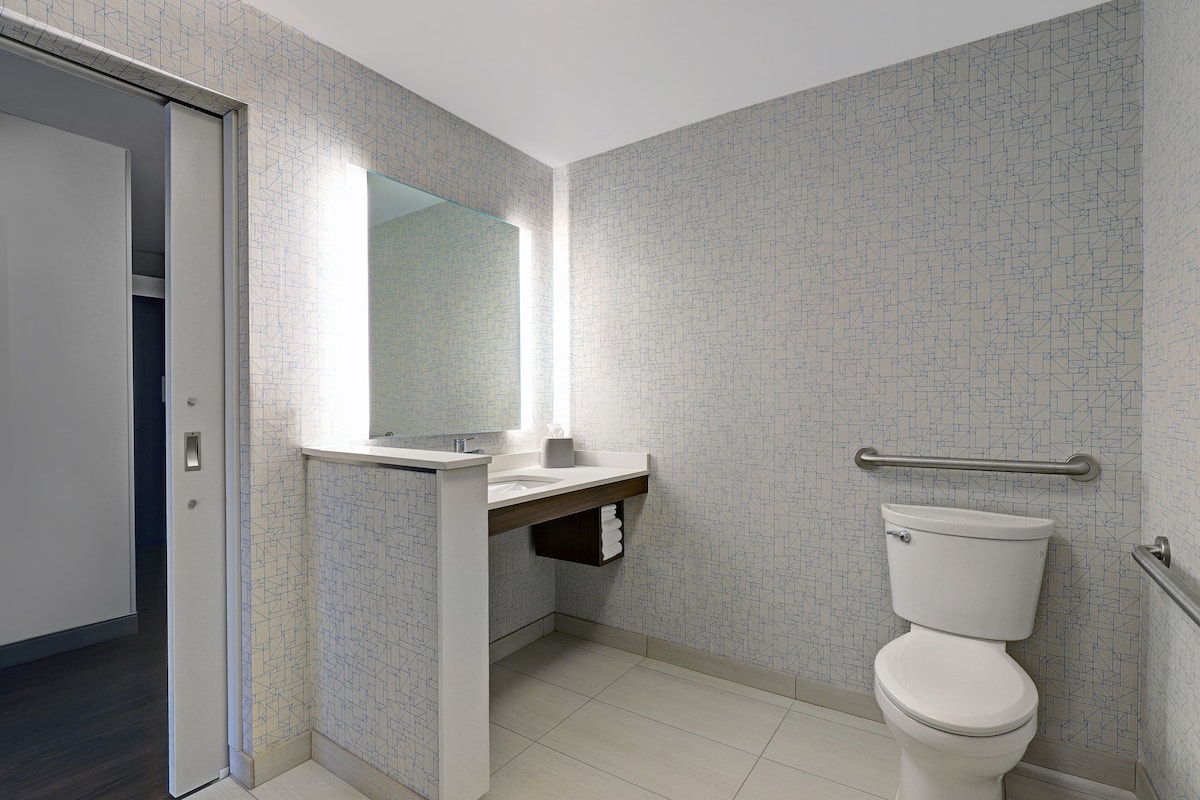 Un baño moderno con inodoro, lavamanos y espejo.