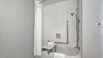 A shower area with a handheld showerhead, a grab bar, and a small shelf with toiletries.