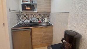 Eine kompakte Küche mit Geschirrspüler, Kaffeemaschine und Mikrowelle auf der Arbeitsfläche.