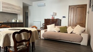 Una sala de estar con comedor, muebles de madera, un radiador y una puerta.