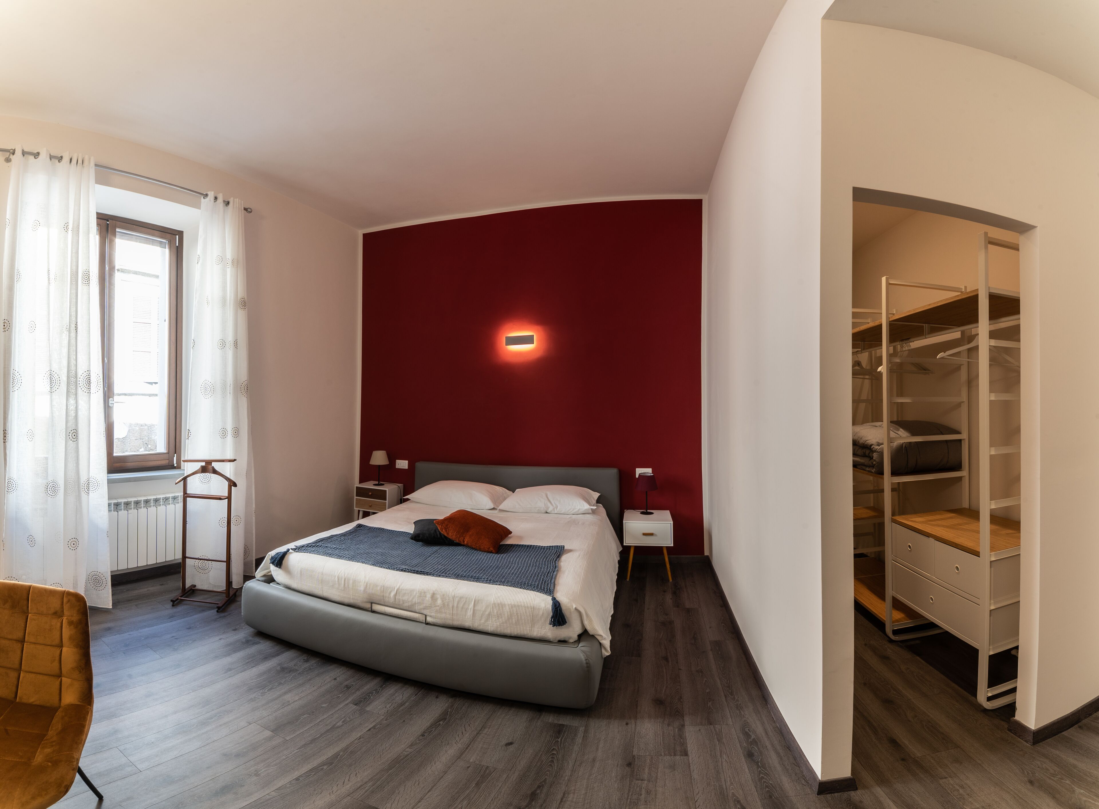 A modern bedroom with a large bed, a wardrobe, and a bedside table.