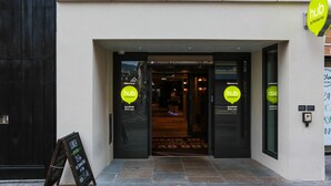 A building entrance with a sign reading 'hub by Premier Inn' and a chalkboard sign outside advertising lunch from 12pm to 2pm. - Hub By Premier Inn London Spitalfields (London)