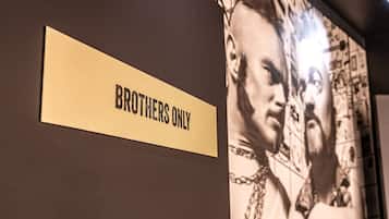 A wall with a sign that reads "BROTHERS ONLY" and a mural of two men.