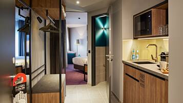 A modern hotel room with a kitchenette, a bed, and a bathroom.