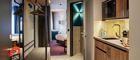Una habitación de hotel moderna con kitchenette, una cama y un baño.