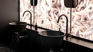 Un baño moderno con dos lavamanos, un espejo grande y una pared con un diseño abstracto complejo.