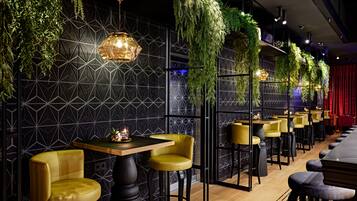 Un restaurante con paredes de diseño geométrico, plantas colgantes e iluminación moderna.