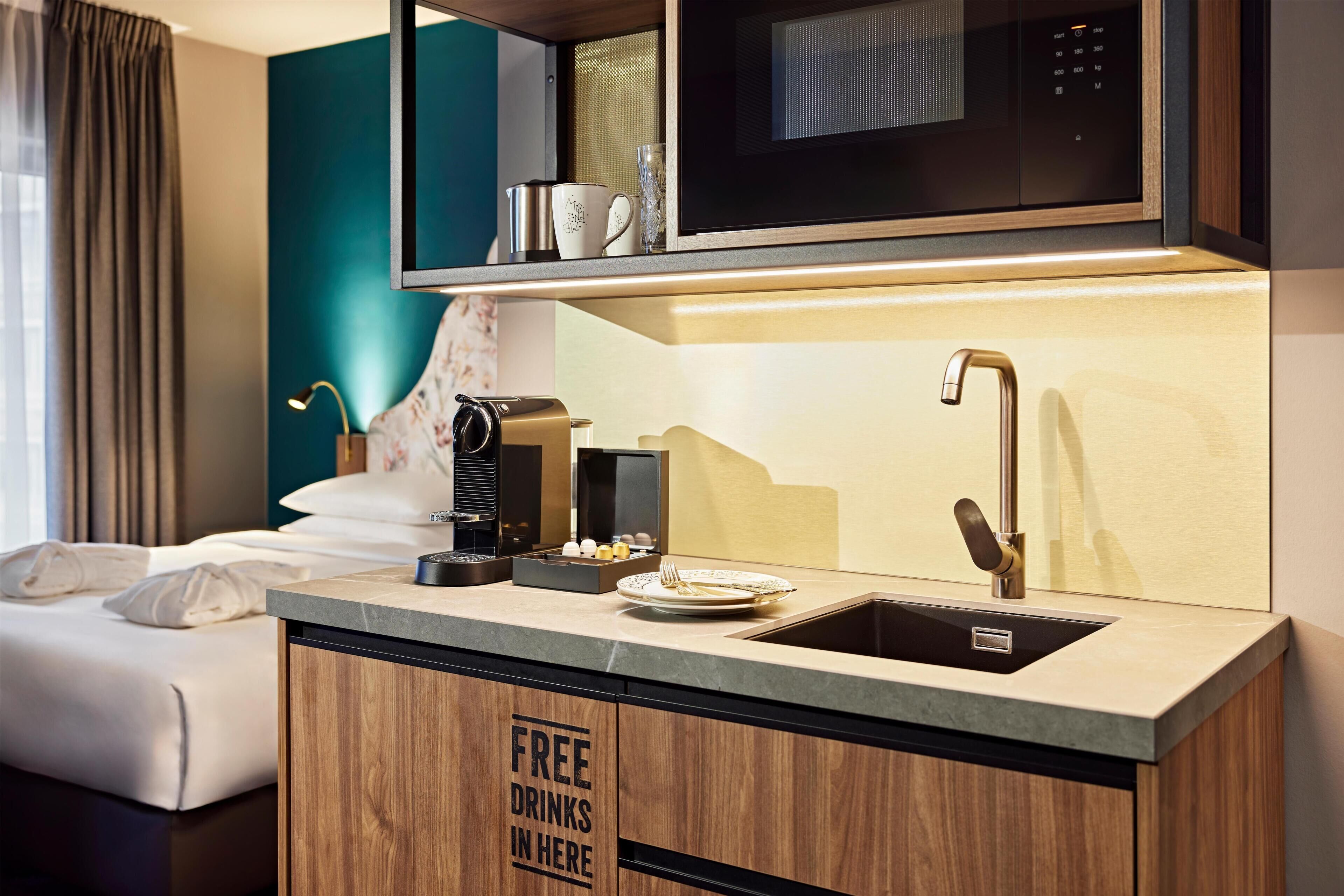 A compact hotel kitchenette with a microwave, coffee maker, and a sink.