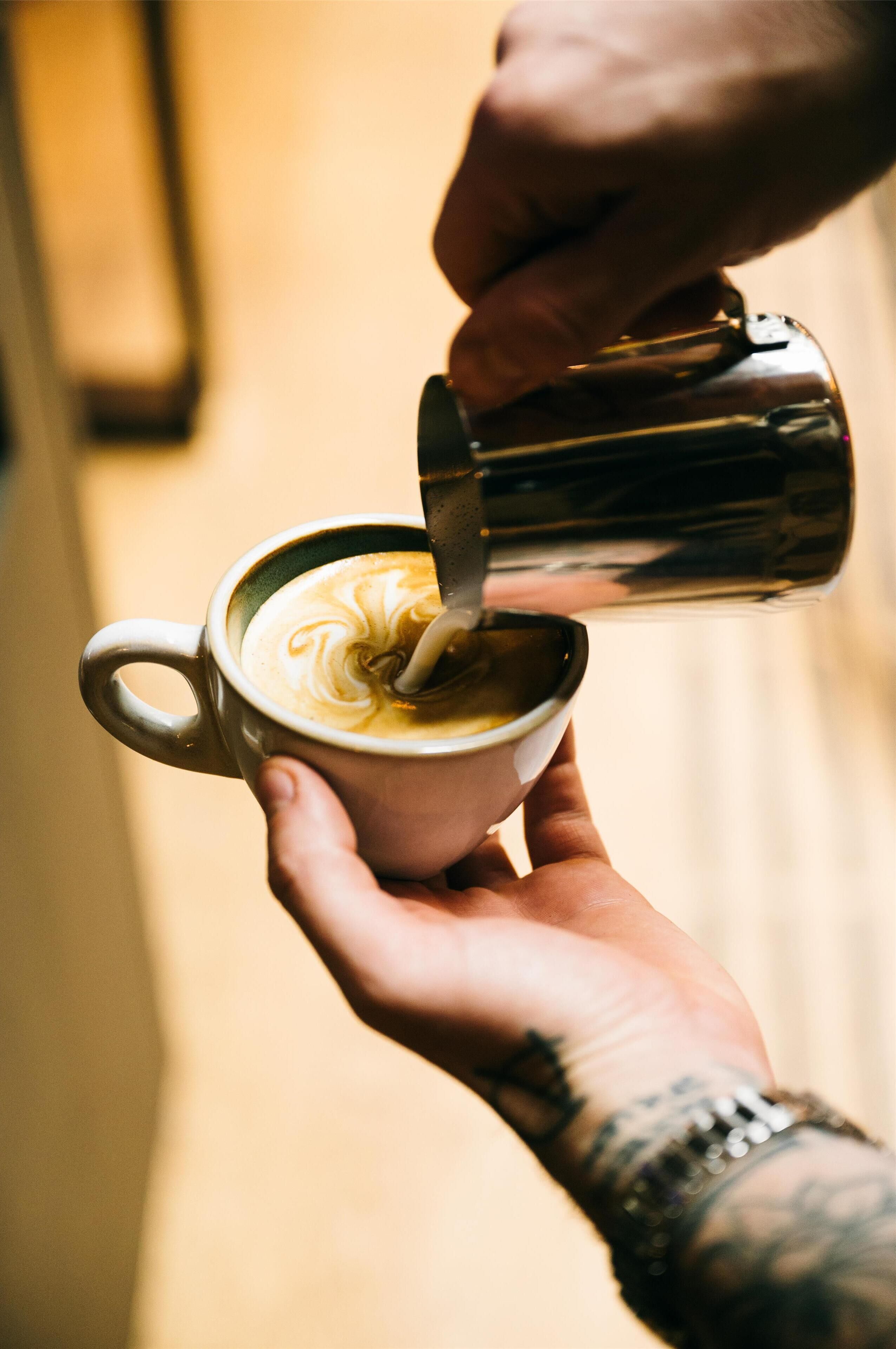 Una persona sosteniendo una taza de café con un diseño artístico de latte.