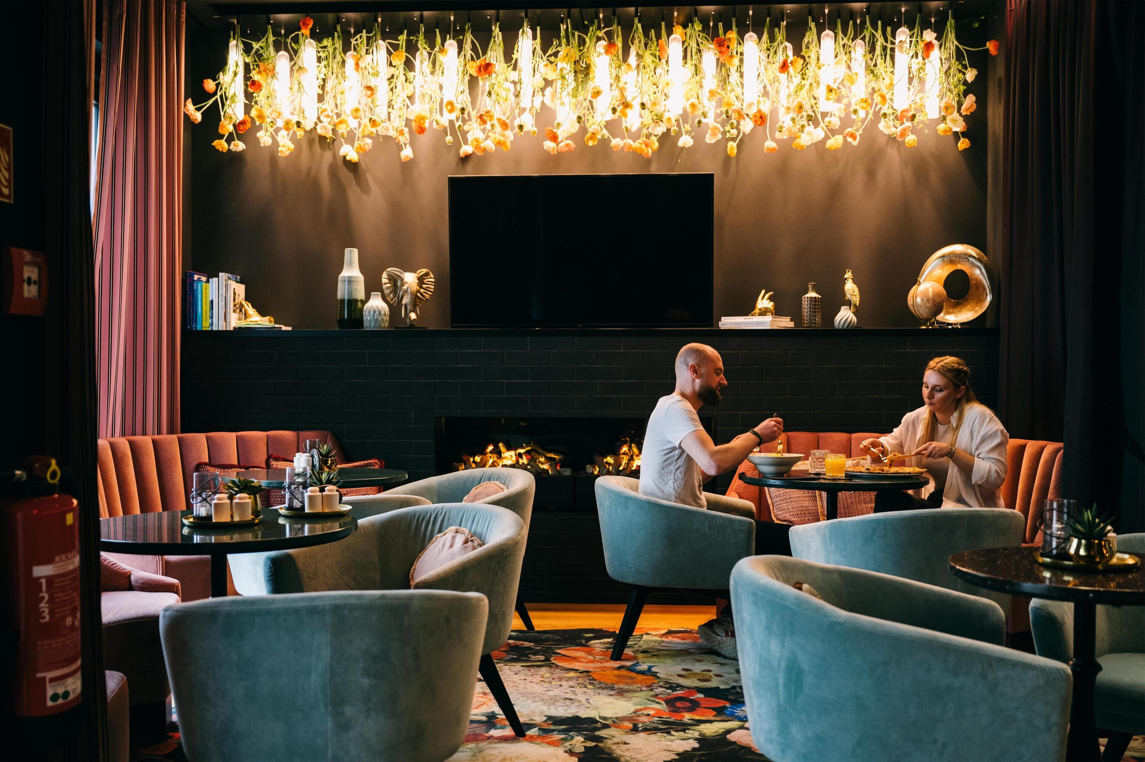 A cozy restaurant with a fireplace, modern seating, and a decorative ceiling light fixture.