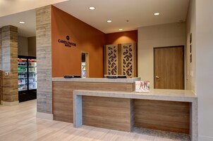 A reception desk with a modern design, a sign reading "CANDLEWOOD SUITES," and a refrigerator stocked with beverages.