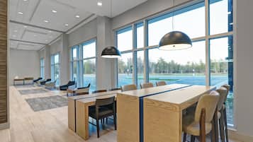A spacious conference room with large windows, a long table, and modern lighting fixtures.
