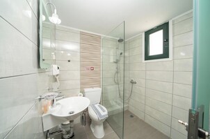 A modern bathroom with a glass-enclosed shower, a white sink, and a toilet.