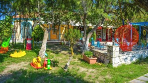 A children's play area with swings, slides, and a climbing structure. - Xi Village (Kefalonia)