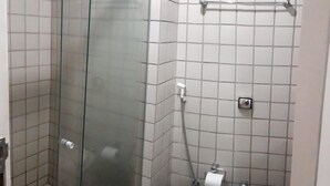Un baño con cabina de ducha de vidrio, inodoro y cubo de basura.