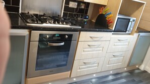 A kitchen with a built-in oven, a microwave, and a gas stove. - Beach Apartment - Kirkcaldy (Kirkcaldy)